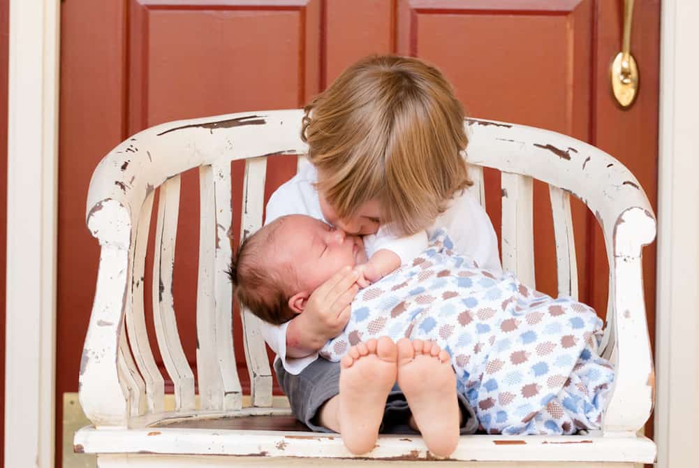 brother kissing baby prepare toddler