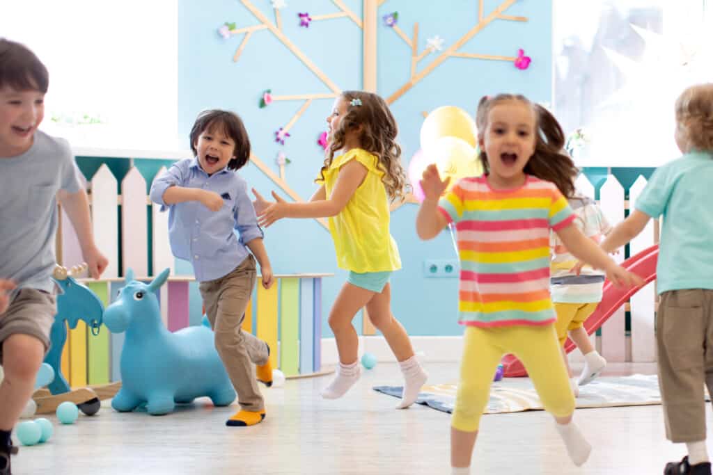 Group of happy children of boys and girls run in day care. Kids play in kindergarten